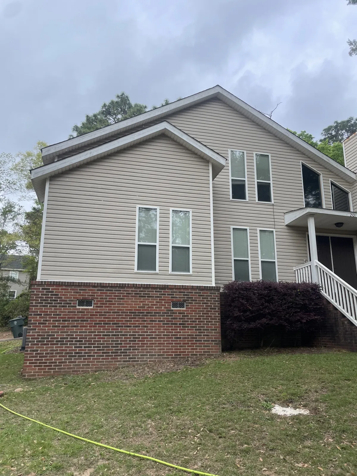 After: soft-washed tan siding and brick foundation on a Daphne, AL home